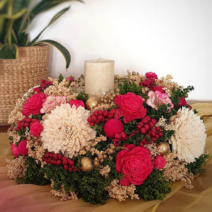 Decorative floral arrangement with red flowers and an LED candle styled in a home.