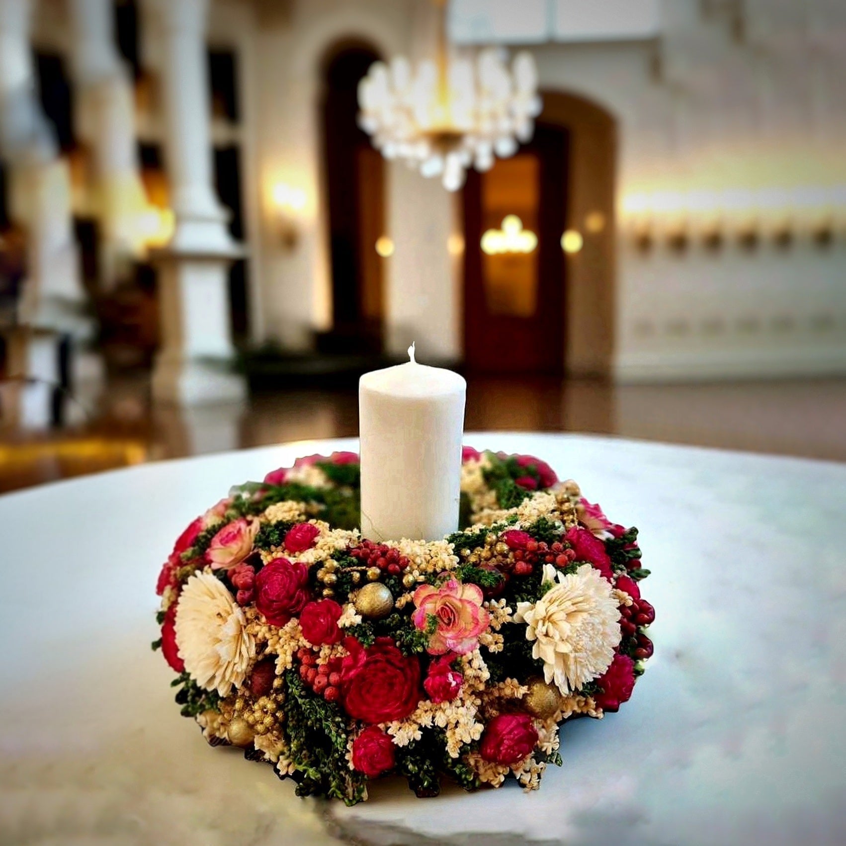 Decorative floral centrepiece with a candle in the center decorated on a marble dining table in a luxurious home.