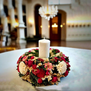 Decorative floral centrepiece with a candle in the center decorated on a marble dining table in a luxurious home.